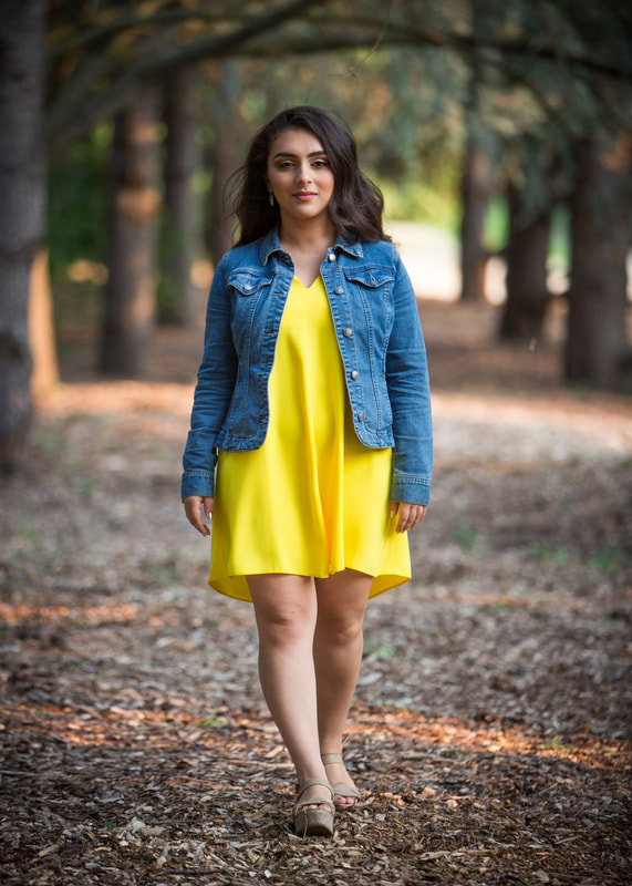 Raya Tuffaha wearing a yellow dress and denim jacket, walking towards the camera